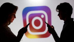 FILE PHOTO: Illustration shows teenagers pose for a photo while holding smartphones in front of an Instagram logo